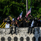 Members of the Proud Boys gesture at the Torch of Friendship, protesting towards people gathered to remember George Floyd on their star anniversary of his death at the hands of a police officer, in Miami on May 25, 2021. - The family of African American George Floyd appealed today for sweeping police reform on the anniversary of his murder by a white officer as they met President Joe Biden at the White House. The legislation being considered to increase police accountability would be named after Floyd, who suffocated after being pinned down under the knee of Minneapolis officer Derek Chauvin on May 25, 2020